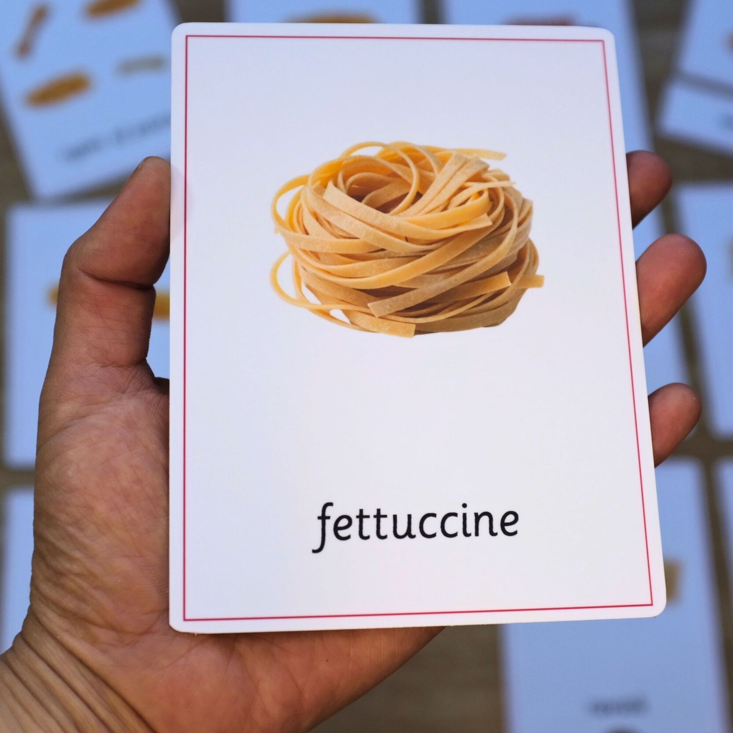 Card with a picture of fettuccine pasta held by a hand
